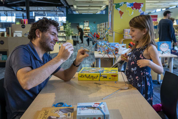 Un père et sa fille jouent à un jeu de société dans la bibliothèque
