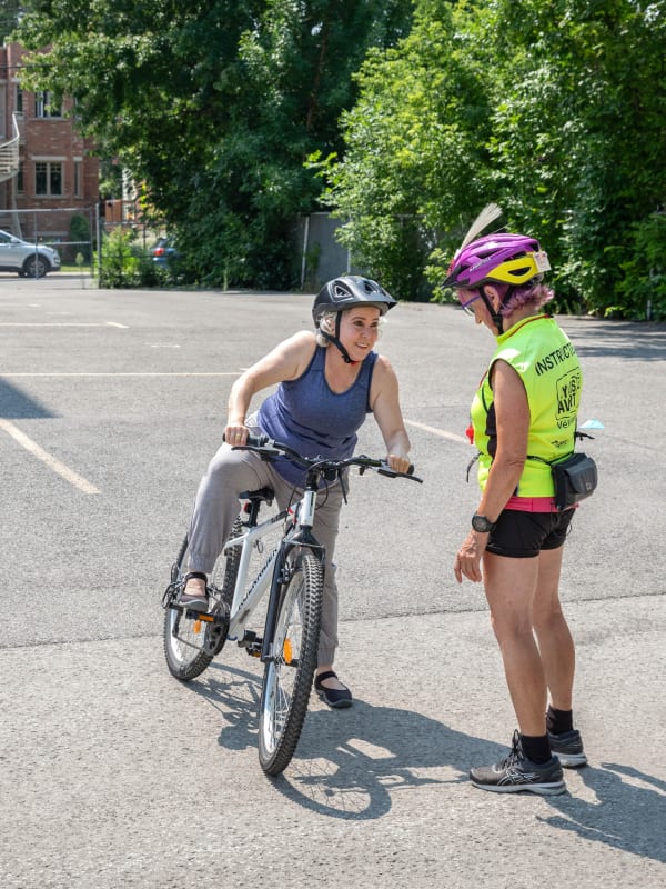 Photo d'une femme qui monte un vélo et qui suit les explications l'instructrice.