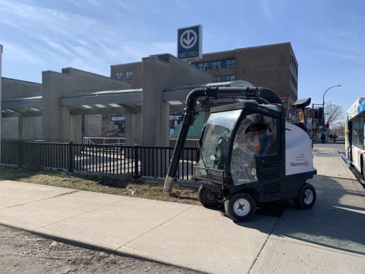 Une voiturette-aspirateur aux abords d'un édicule de métro.