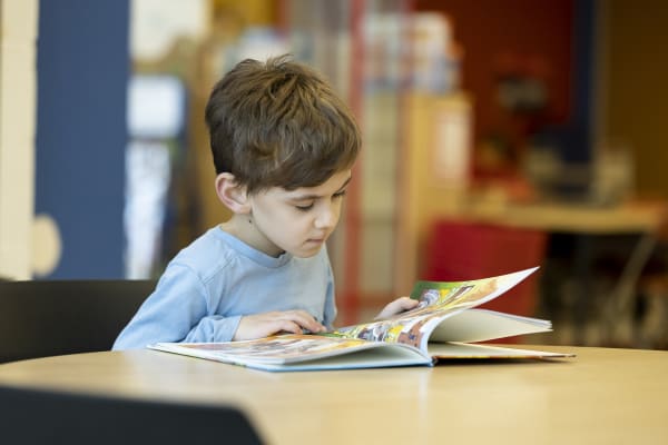 Enfant qui lit un livre en bibliothèque
