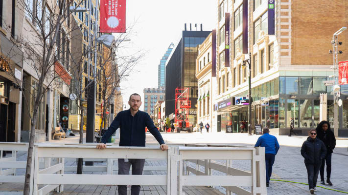 Alexis devant une terrasse dans le Quartier des spectacles au printemps