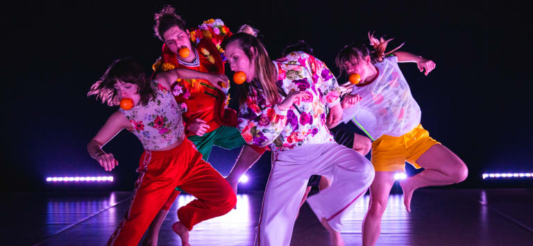 Les danseurs de la troupe sur scène avec une clémentine dans la bouche
