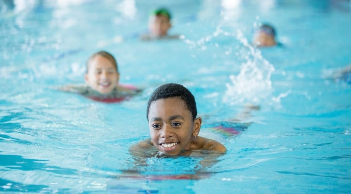 Enfants jouent dans une piscine intérieure.