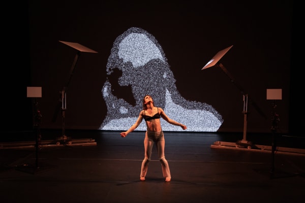 Une femme danse sur scène sur fond d'art numérique.