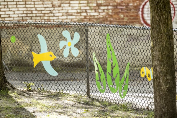 Photos d'éléments en aluminium sur la clôture du parc représentant un oiseau, une fleur et une plante