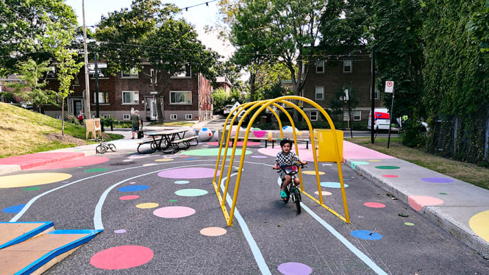 Un petit garçon circule à vélo le long d'un parcours coloré tracé au sol