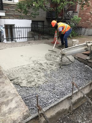 Henri entrain d'égaliser le béton au rythme de la bétonnière