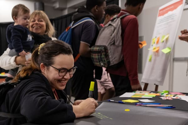 Une citoyenne écrit une idée à l'une des stations disponibles lors du Forum sur la bouffe qui s'est tenu le 5 novembre 2024, dans le cadre de la démarche de consultation sur le Plan de développement d'une communauté nourricière