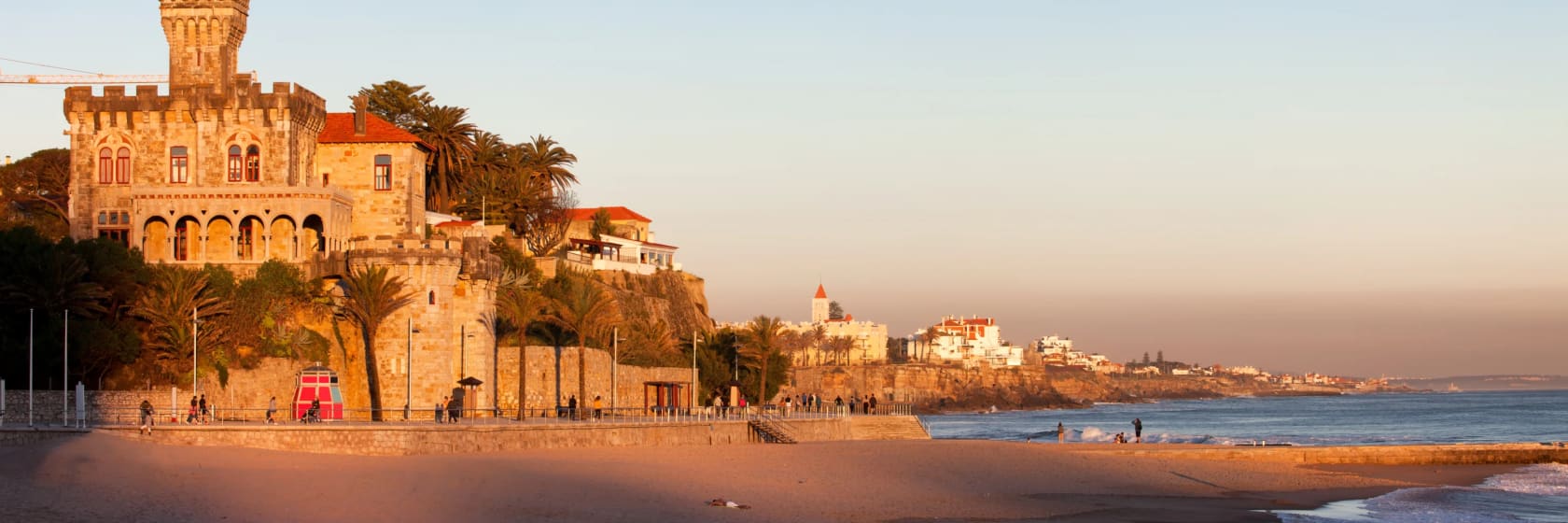 Roligt landskab ved Atlanterhavet, Tamariz Beach overset af et slot ved solnedgang i feriebyen Estoril i Portugal