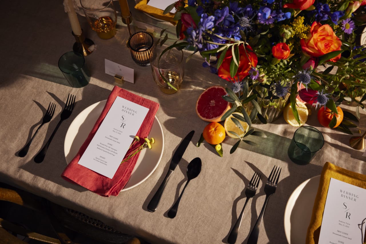 A floral arrangement on a wedding table with a place setting and menu