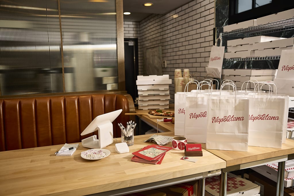 A range of food packaging in an Italian restaurant including cardboard boxes, paper bags and paper cups