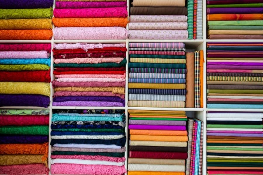 Shelves filled with folded fabrics in a wide range of colors, textures and patterns.