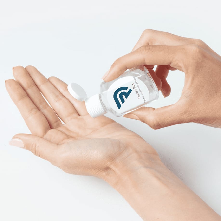 Woman applies hand sanitizer from a branded travel-size container.