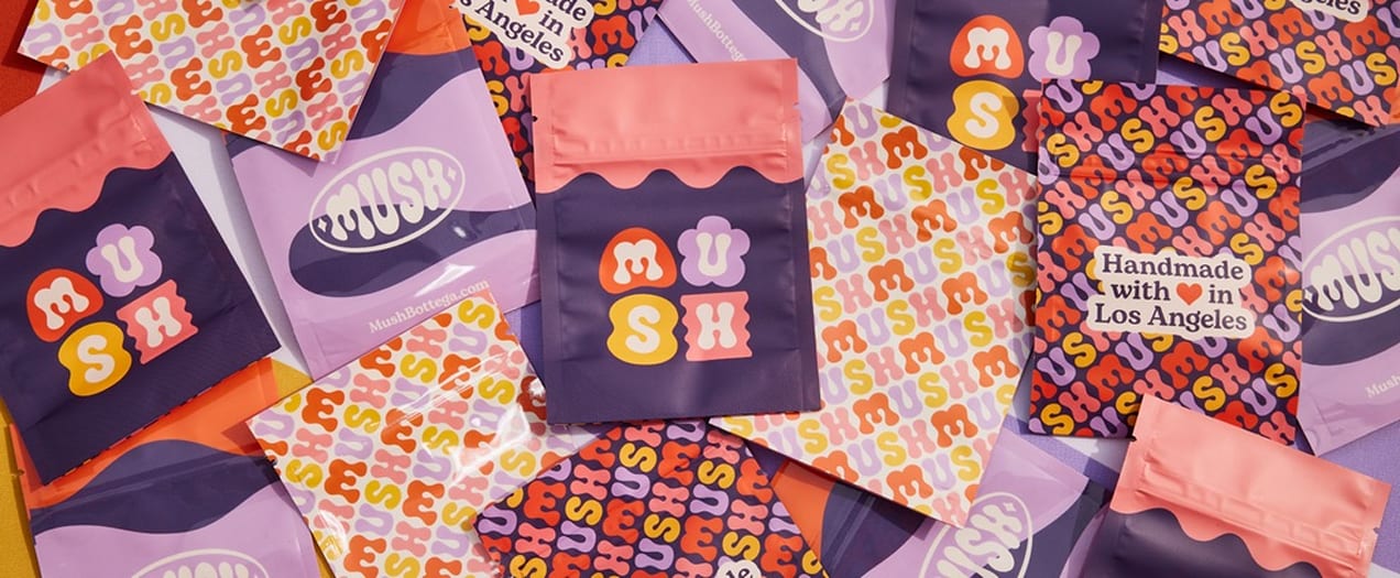 A display of branded packaging including pouches, paper bags and tissue paper.
