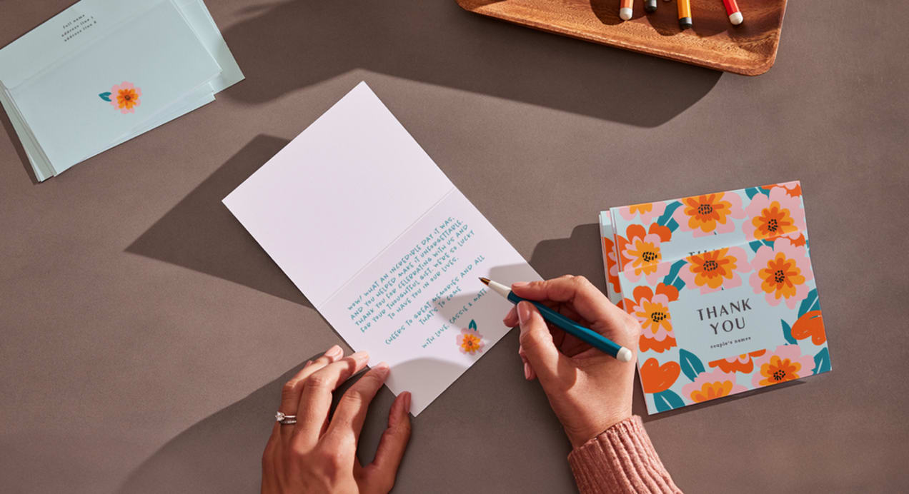 Person writing custom message on a branded business thank you card to add to orders