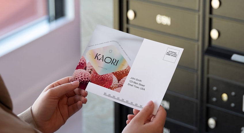 A person holding a branded postcard with the brand logo and custom holographic sticker