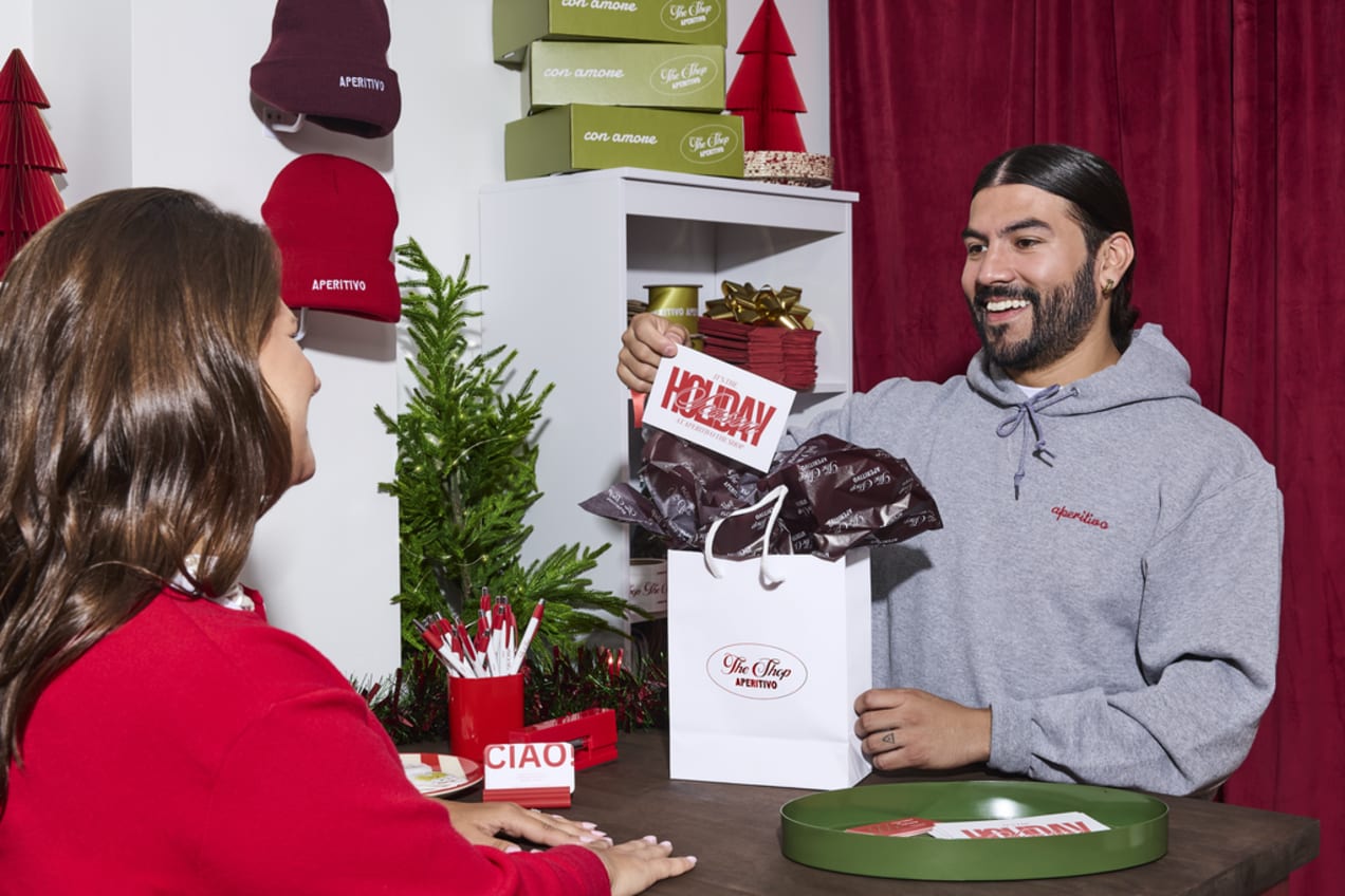 Business owner hands a branded Christmas card to a client with a gift bag.