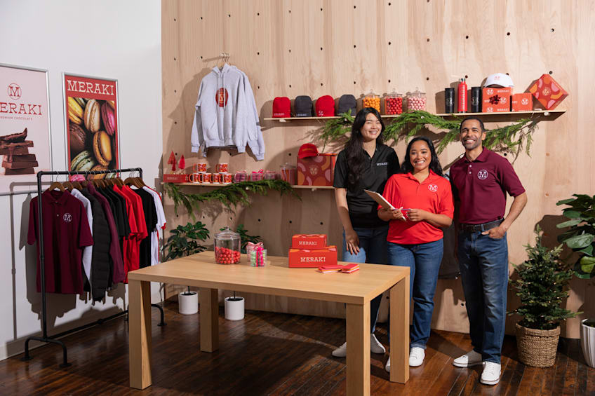 Meraki store employees standing behind a table wearing branded polos for a business holiday event