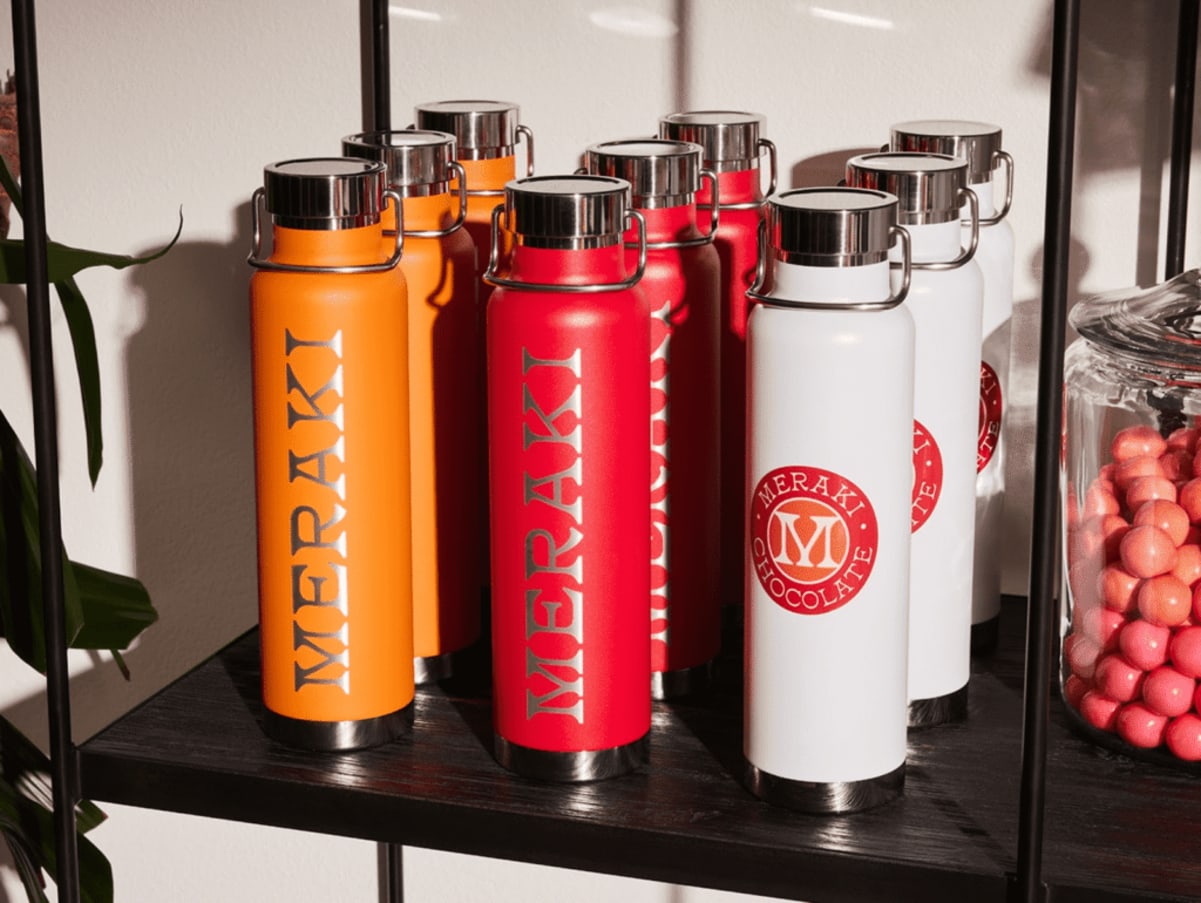 Selection of “Meraki Chocolates” branded water flasks in red, orange and white.