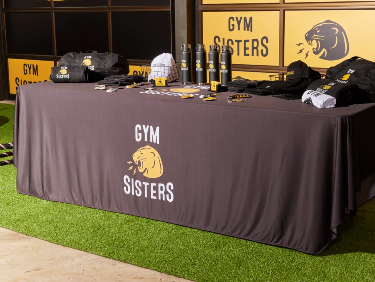 A selection of brand merch: branded water bottles, T-shirts, hats and tote bags at a trade show