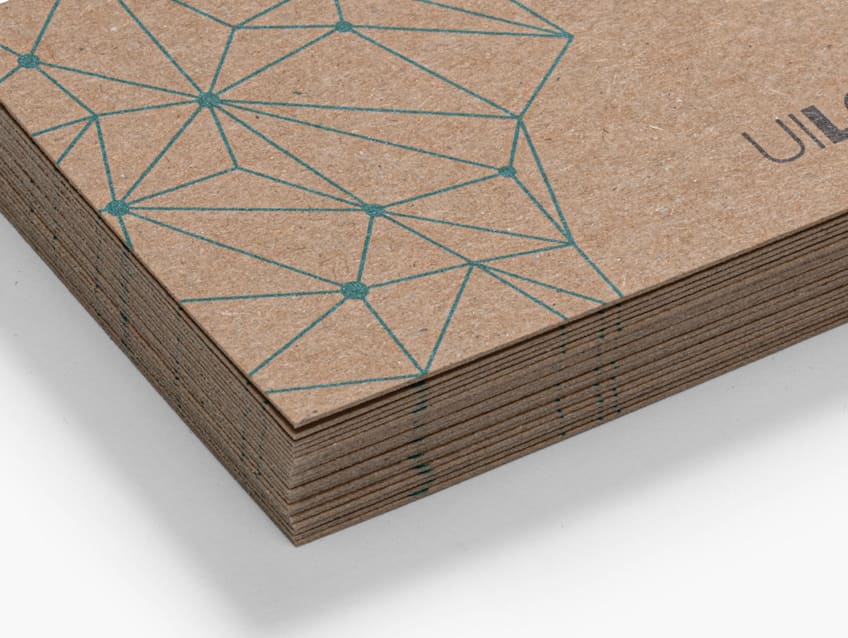 Close-up of a stack of recycled kraft business cards with a teal geometric line design.