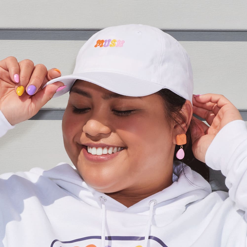Smiling woman wearing branded white cap with colorful logo