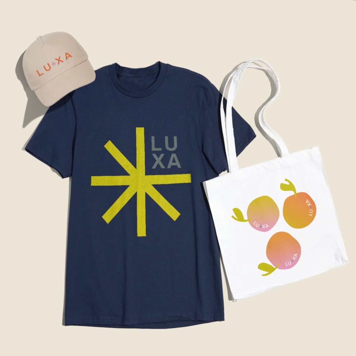 Different logo designs on a cap, tote bag and T-shirt