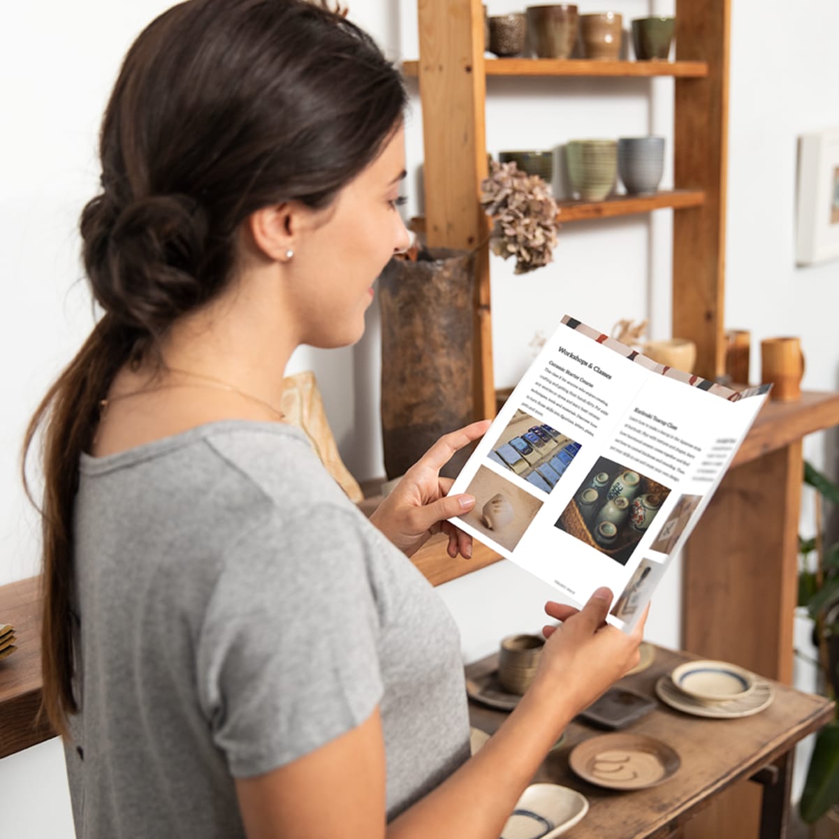 A customer reading a tri-fold brochure design for a ceramics business