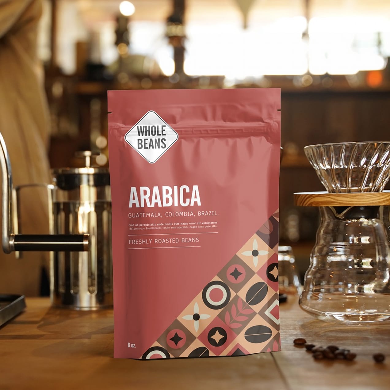 Matte coffee bag labeled Arabica standing on a wooden counter next to a pour-over setup in a café.