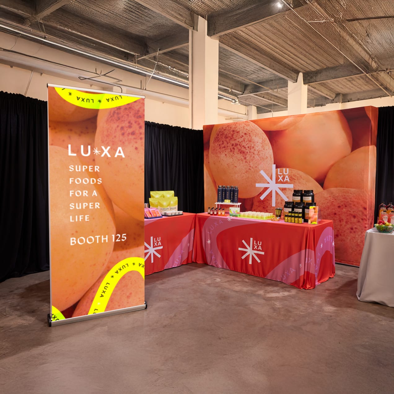 An event stall for a health food business featuring branded large retractable banner, back display, table cover all in red, orange and yellow theme