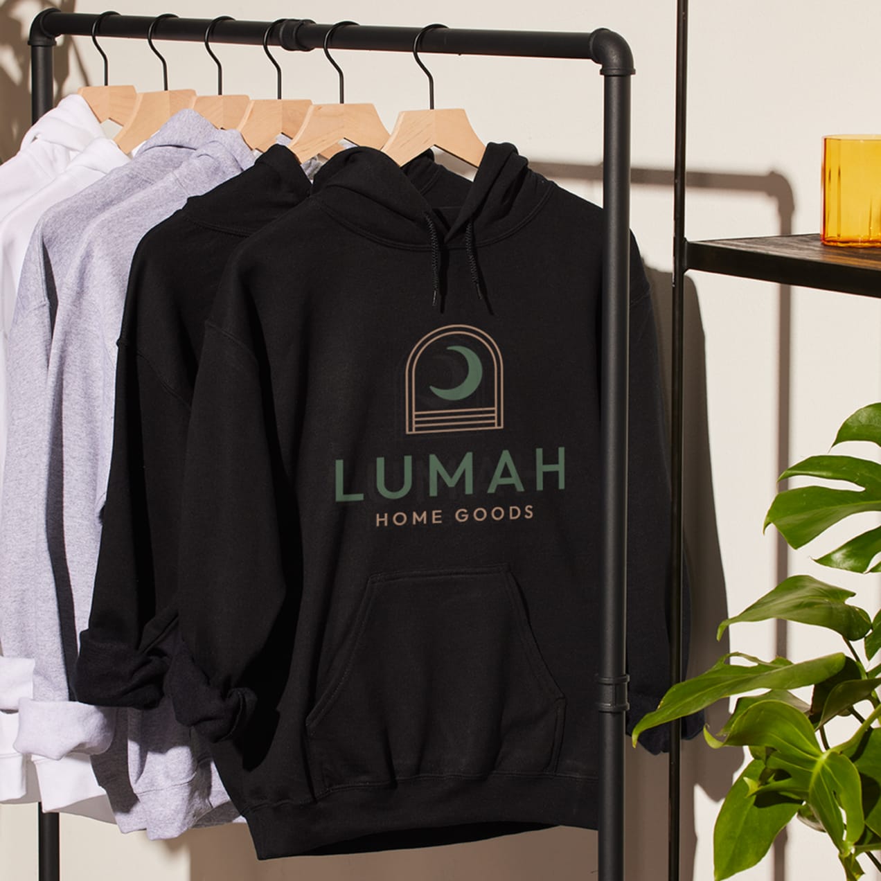 A rail with black, grey and white hoodies hanging with a large logo printed on the front