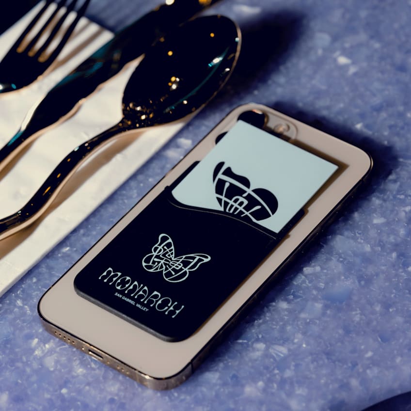 A branded card holder on the back of a phone, next to a set of cutlery