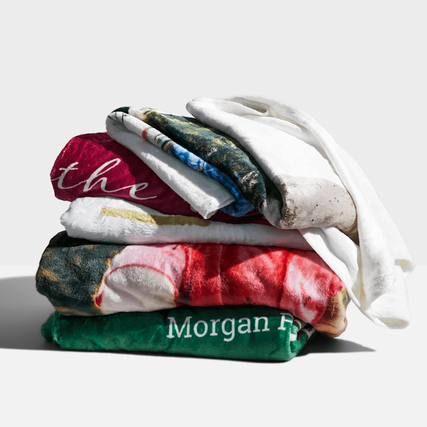 A pile of cosy custom fleece blankets, best corporate holiday gifts for employees