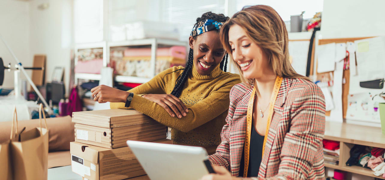 Two small business owners using a tablet to promote an upcoming event.