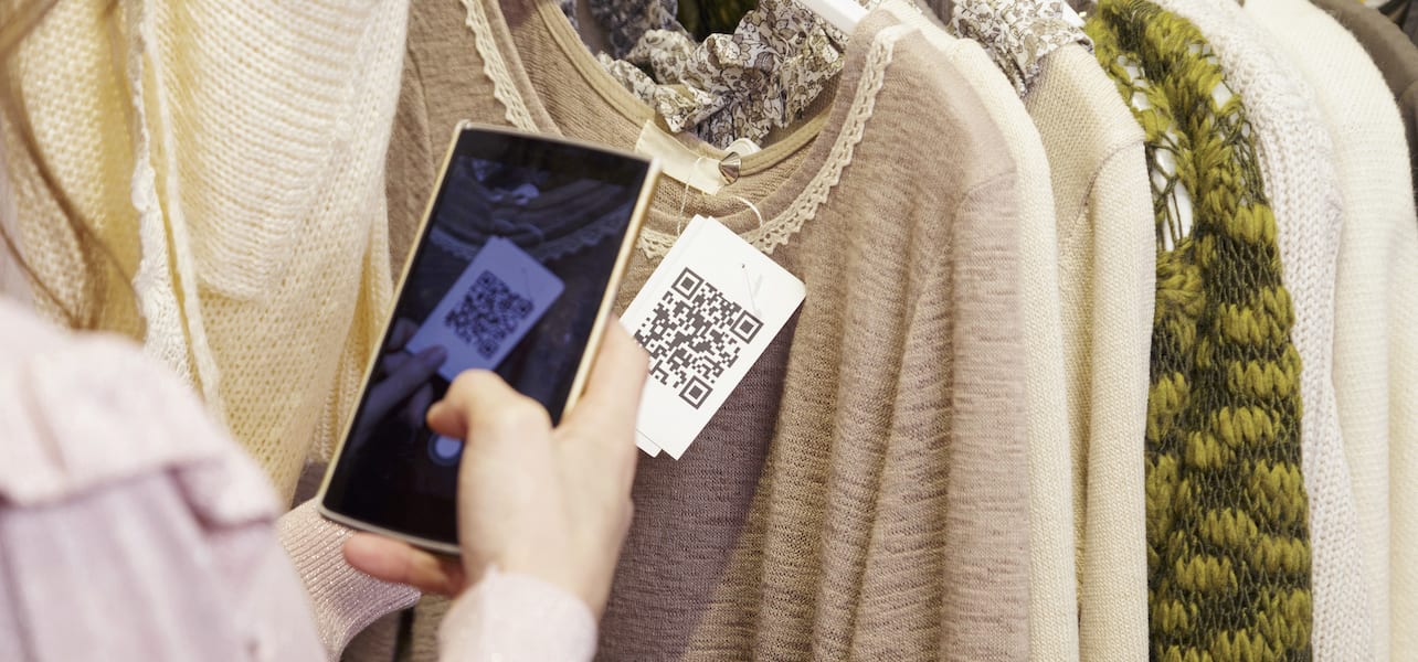A retail customer scans a QR code on a clothing product tag.