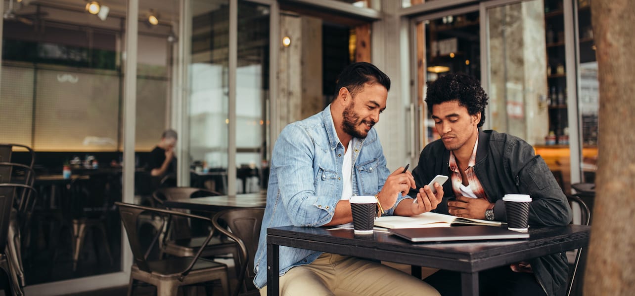 Two people discuss business outside of a coffee shop