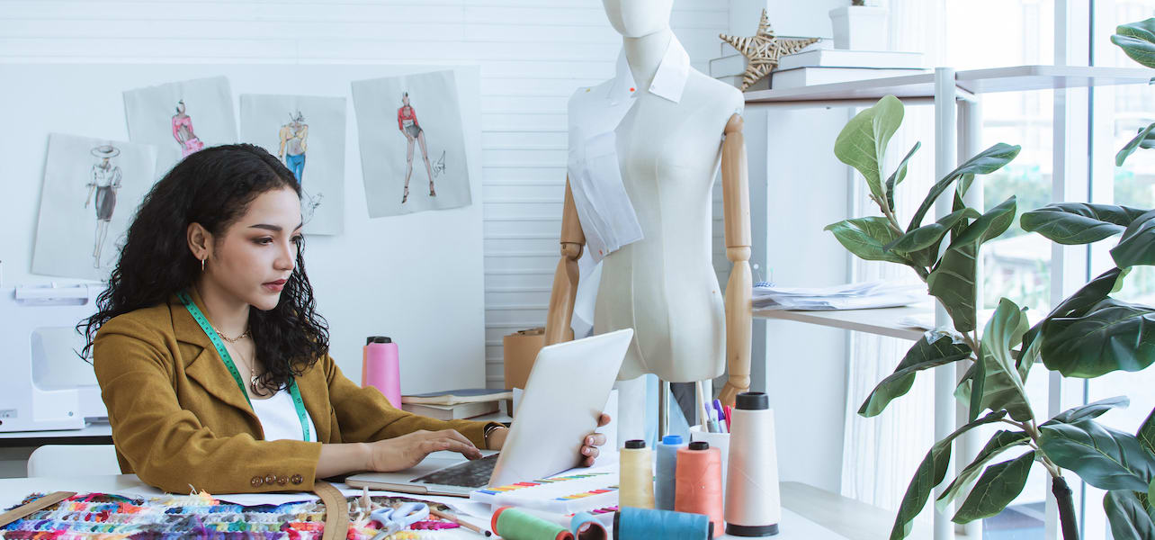 A tailor in her shop browsing online resources for small business owners