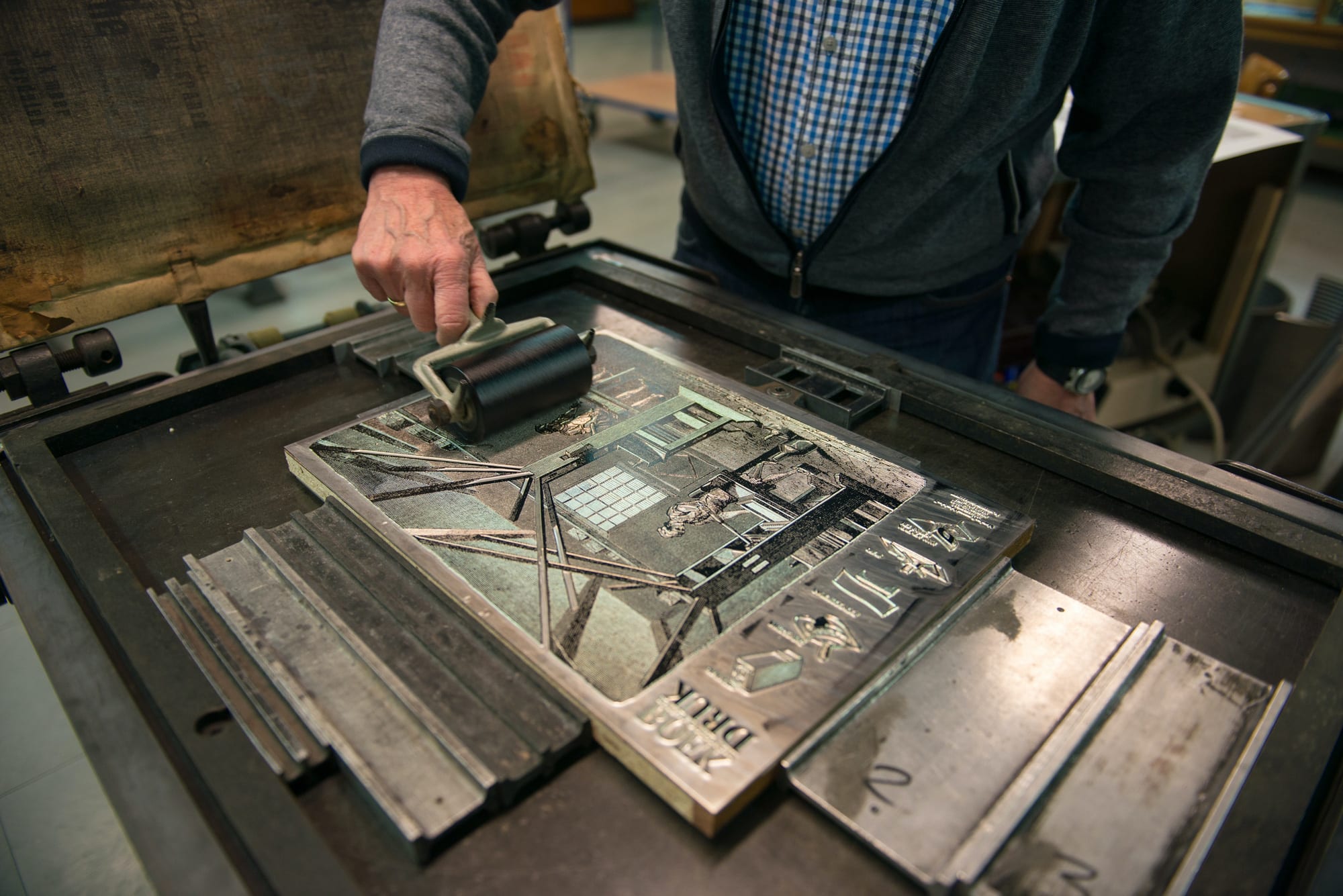 Close-up of man’s hand rolling ink on a printing form on a letterpress