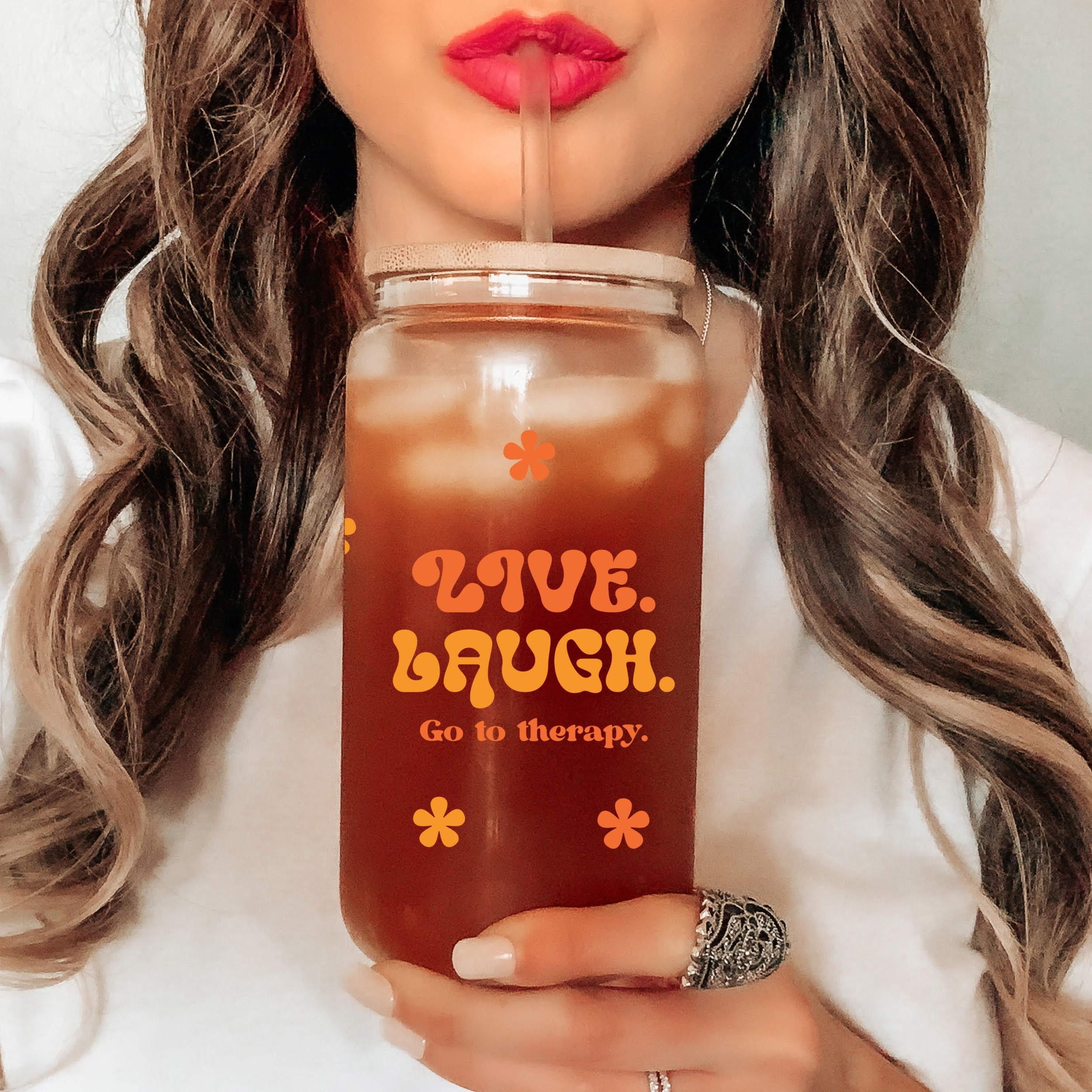 Person drinking from glass jar that reads, 'live. laugh. go to therapy