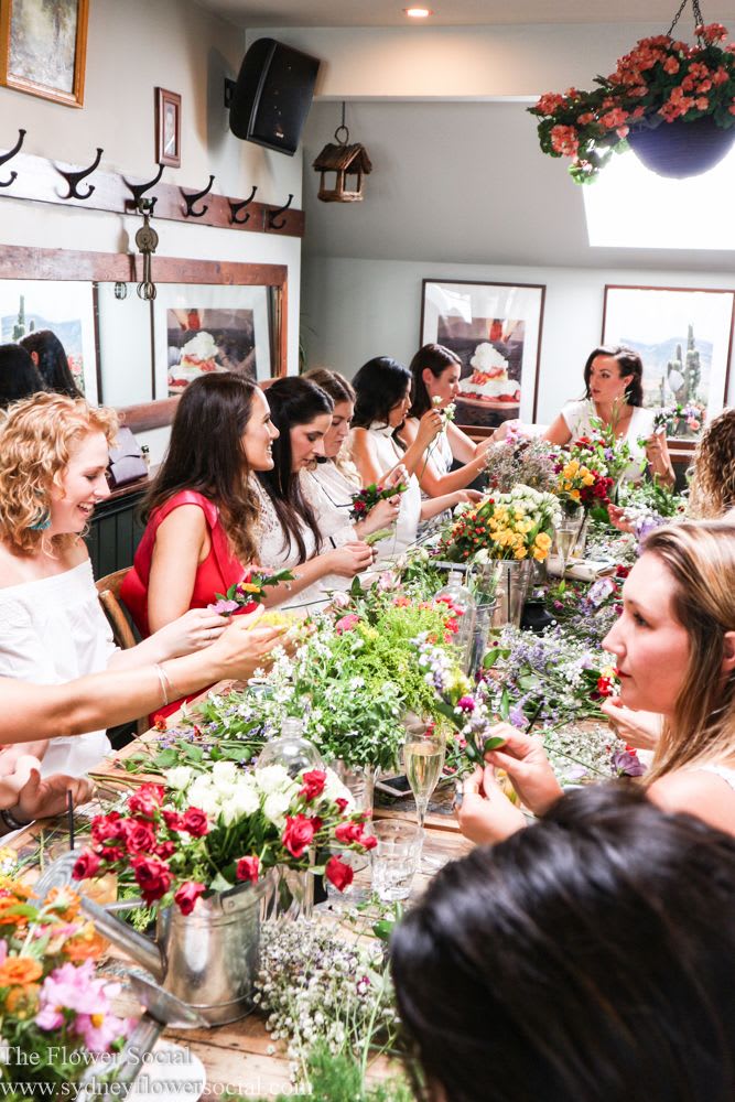 A group of people sitting at a long table with flowers