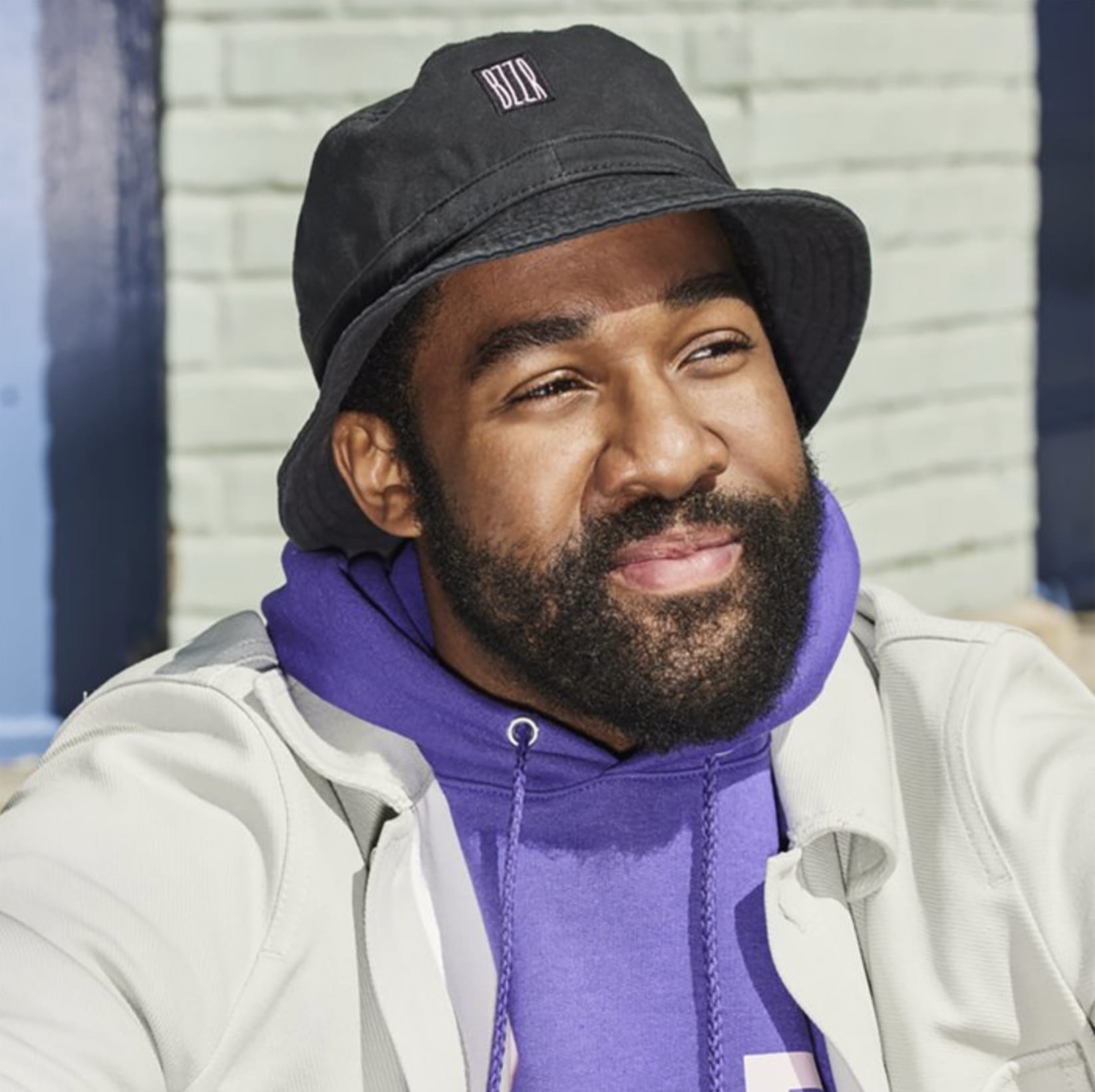Happy man wearing a cotton bucket hat with a small square fabric logo stitched to the forehead