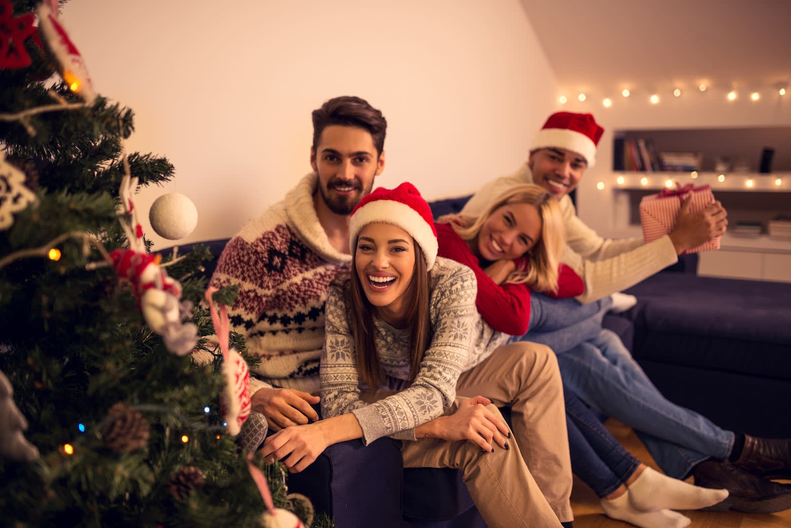 Friends sitting on a coach celebrating Christmas together