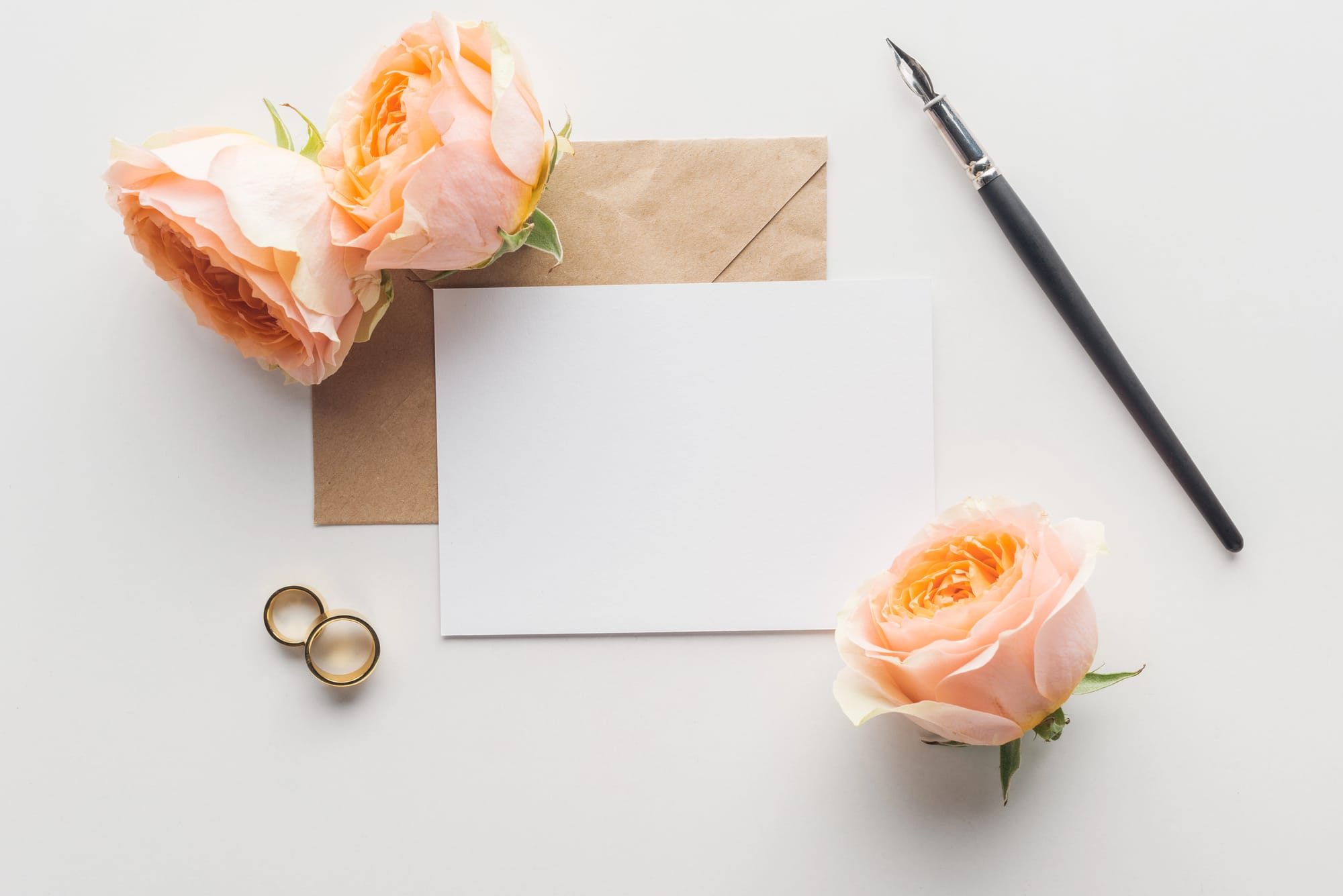 Wedding card with peach roses, rings and a pen