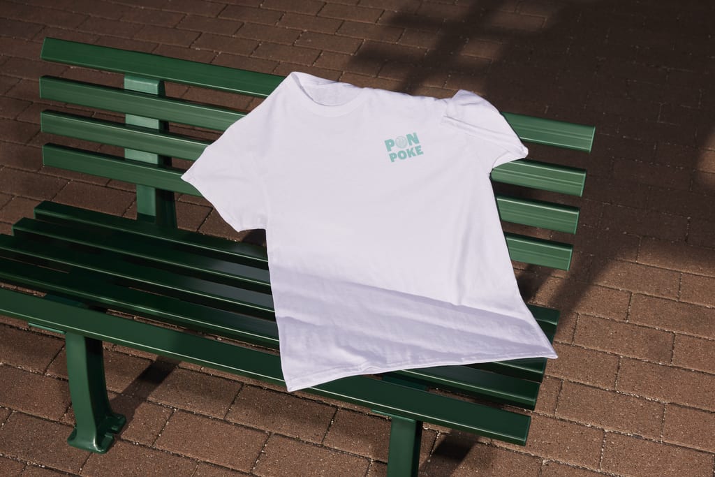 T-shirt with a logo on the left chest resting on a bench