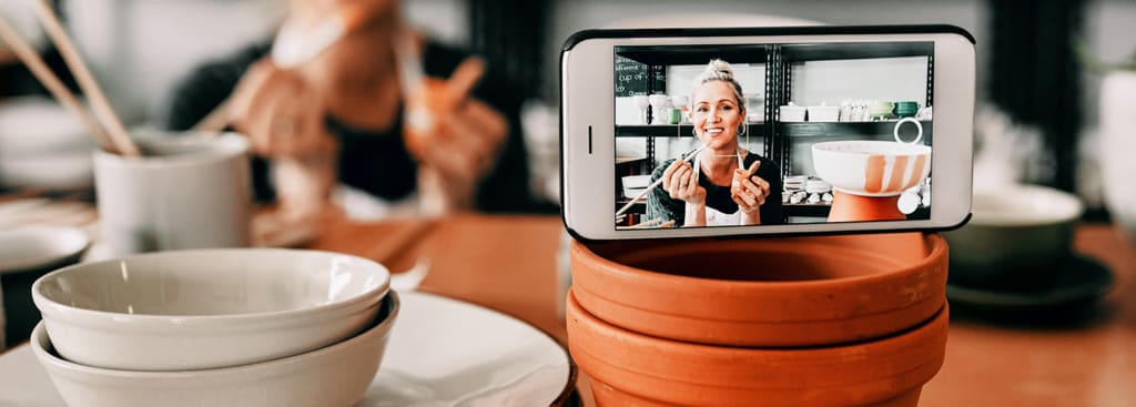 phone resting on pot with small business social media influencer on the screen