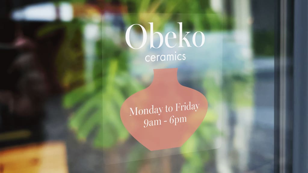 Storefront with wooden decor and indoor plants in the background, featuring a transparent logo sticker with business hours on the glass.
