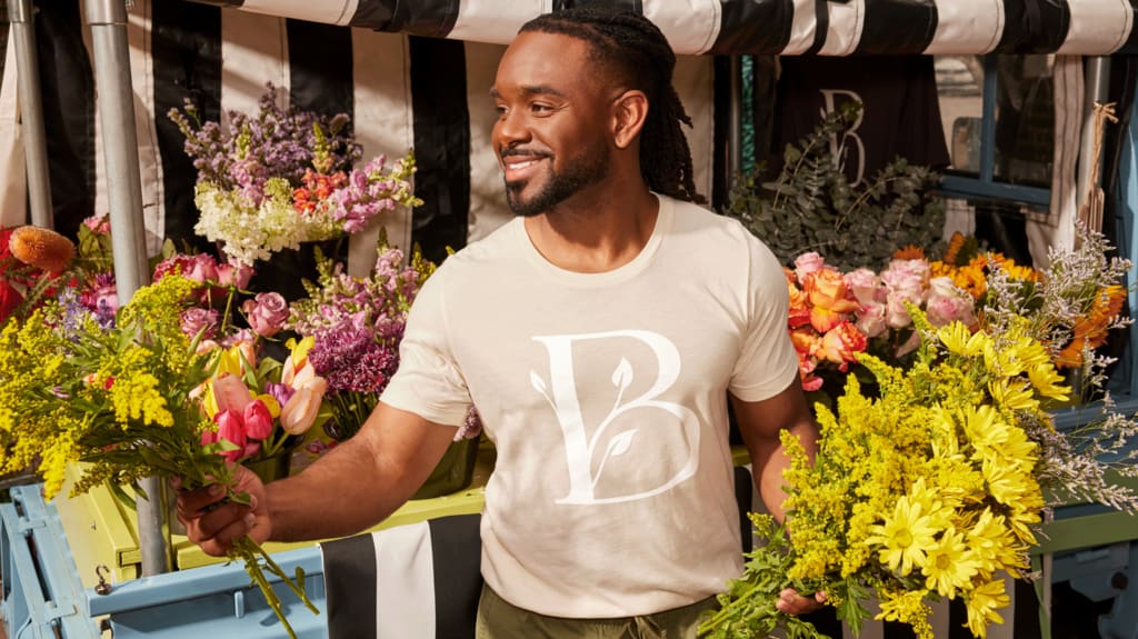 Florist handing a colorful bouquet to a customer outside his shop, showcasing a vibrant small business startup.