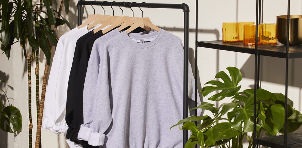Blank hoodies and sweatshirts hung on a clothing rack