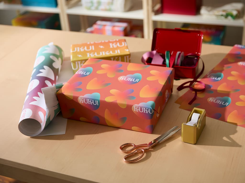 Wrapped gifts laying with colorful wrapping paper on a table.