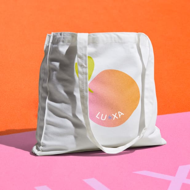 A white tote bag with a brand logo printed on the front